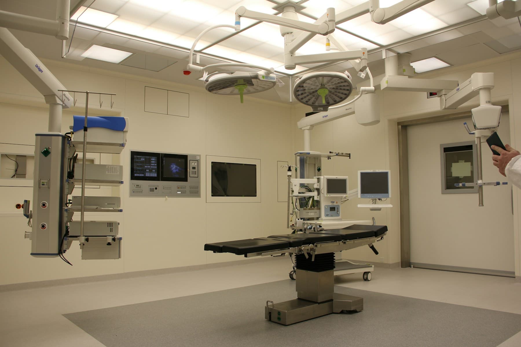 Modern robotic-surgery operating room with overhead surgical lights and a surgical table